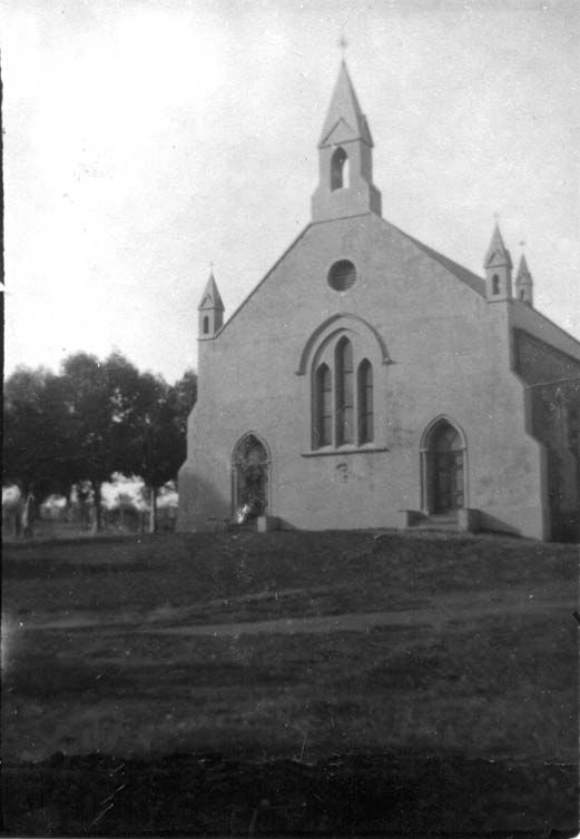 Black-and-white photograph of Morphett Vale Baptist Church — a rendered church with a pointed steeple, rose window, Gothic arched windows in the nave, and corner turrets, in a grassy paddock