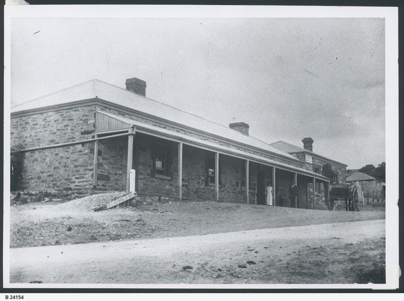 Black-and-white photograph of the Victory Hotel at Aldinga — a long single-storey stone building with a verandah running the full length, multiple chimneys, and a horse and cart to the right