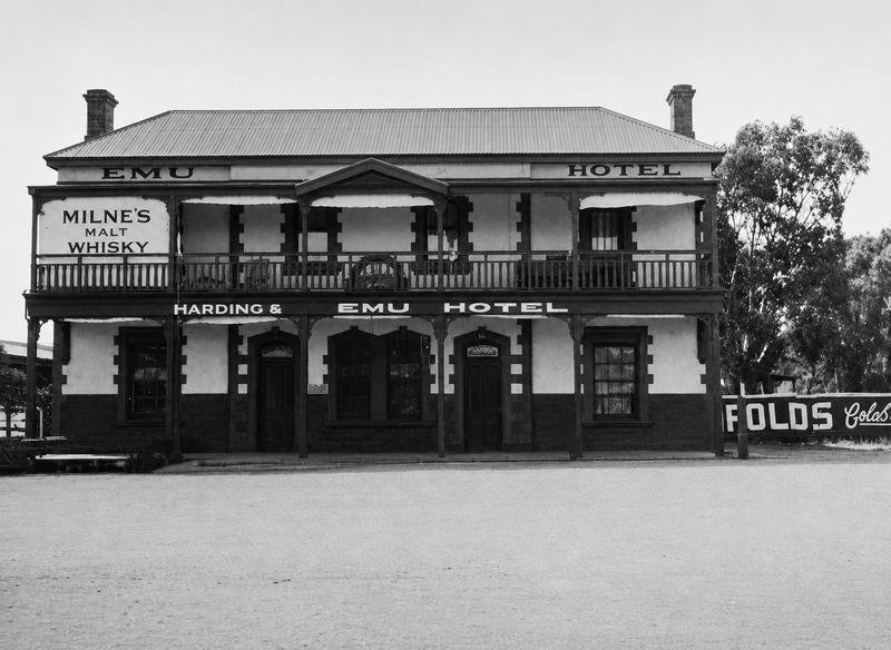 Black-and-white photograph of the Emu Hotel, Morphett Vale — a two-storey building with verandah, Emu Hotel painted across the roofline, Harding and Emu Hotel on the ground floor, and a Milne's Malt Whisky sign