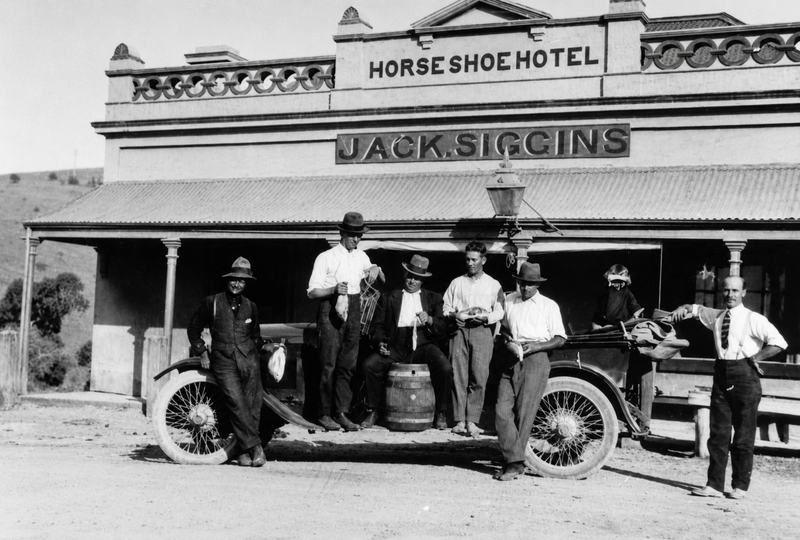 Black-and-white photograph of seven men standing around an early car outside the Horseshoe Hotel, the facade reading Horse Shoe Hotel and Jack Siggins with a decorative parapet