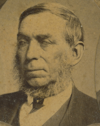 Sepia head-and-shoulders portrait of an elderly man with grey hair and a chin-curtain beard along his jaw and clean-shaven upper lip, wearing a dark coat, waistcoat and tie, looking slightly to one side