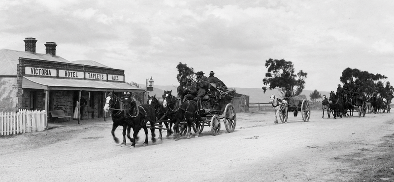 Black-and-white photograph of the Victoria Hotel at Tapley's Hill with a four-horse coach passing the front, the hotel facade visible on the left, horse vehicles on the dirt road