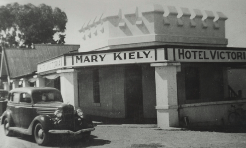 Black-and-white photograph of the Hotel Victoria — a rounded-corner rendered facade with Mary Kiely — Hotel Victoria lettered across it and a 1930s car parked outside
